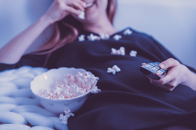 Viewer with popcorn watching a live event on TV