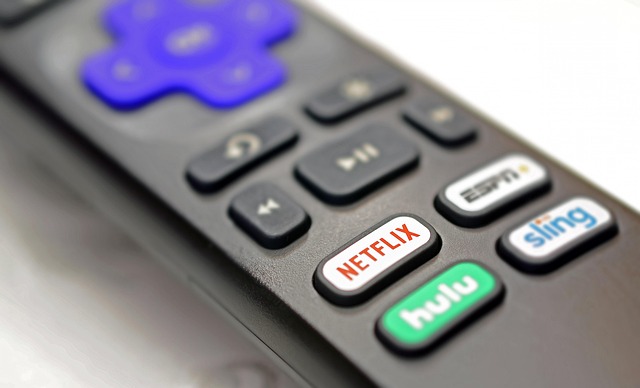 Hand holding a TV remote pointed at a streaming app
